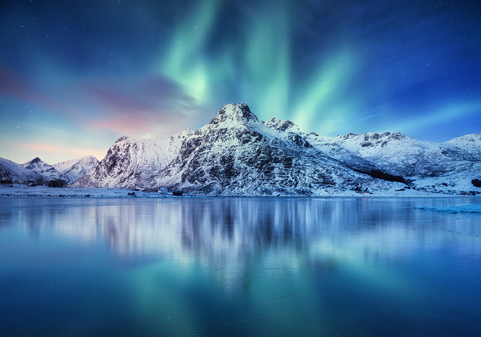 Aurora Borealis, Lofoten islands, Norway. Northern light, mountains and frozen ocean. Winter landscape at the night time.