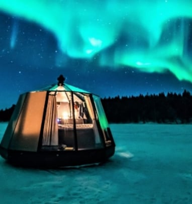 Overnattingstelt med nordlys i bakgrunnen. 