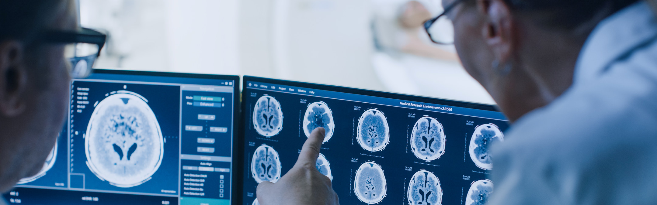 Lege og radiolog diskuterer resultater av hjerneskanninger som de ser på en skjerm. 