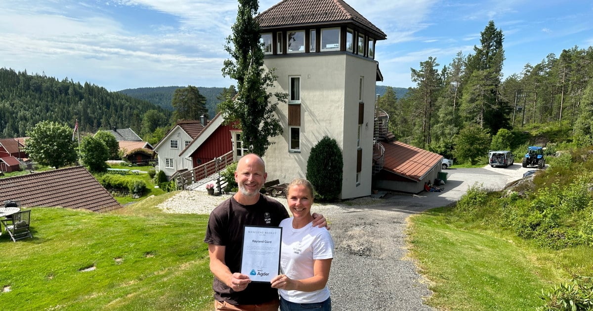 Ekteparet Gunnar Sagstuen og Pernille Vea foran Røyland Gård med diplomet for månedens bedrift juni 2025 fra NHO Agder.
